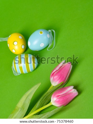 Easter eggs and tulips on green background with copy space