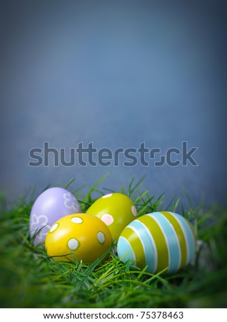 Easter eggs in green grass with copy space and blue background
