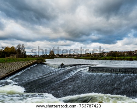 Flowing water at a canal with weir in the foreground using long exposure photography
