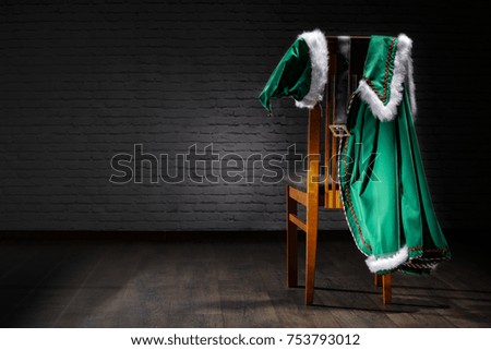A chair in the house of Santa Claus and costumes on the back.