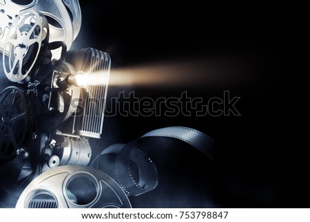 Cinema background with movie projector and film reels on a dark background / high contrast image