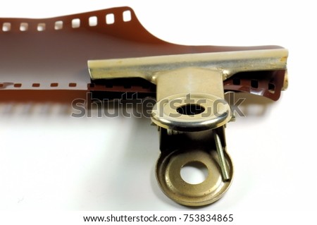 Film strip on a white background with metal clip.