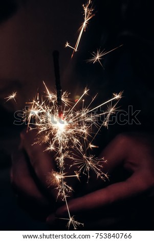 hand holding a burning sparkler bengal light. space for text. burning sparkler closeup in female hand in dark. happy new year and merry christmas concept. happy holidays, pyrotechnics concept