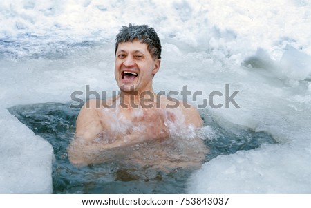 A man is swimming in an ice hole in the winter