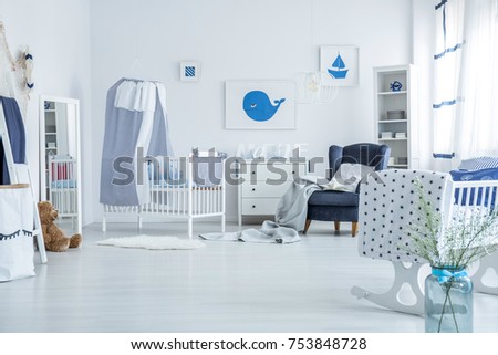 Spacious kid's bedroom with cradle, mirror and whale and boat posters on white wall