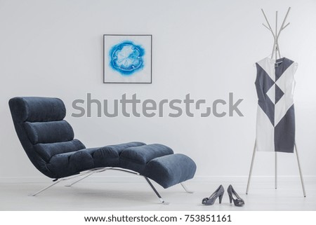 Elegant shoes and dress with geometric pattern in bright dressing room with poster and soft couch