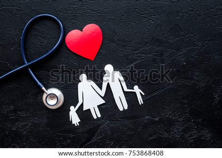 Choose health insurance. Stethoscope, paper heart and silhouette of family on black stone background top view.