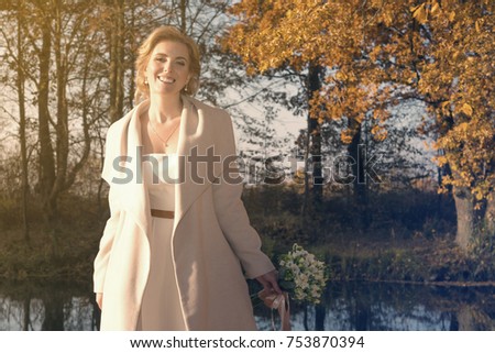 beautiful woman in a coat and a white dress for a walk in an autumn park or forest. retro wedding style 50-ies.