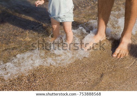 close up picture of father and kids legs in water at summer vacation