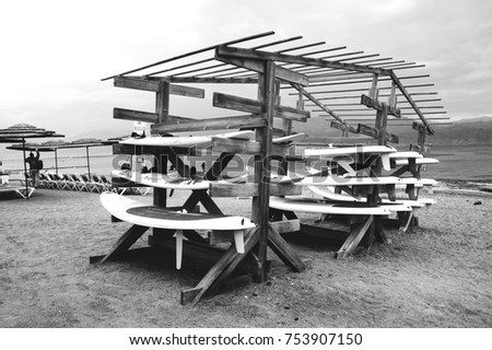 Surfboard stack on the beach. Eilat (Israel) is popular winter sun escape destination proposing various leisure and recreation activities. Black White photo.
