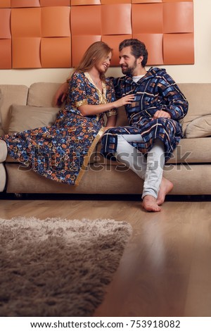 Image of woman and man in home clothes hugging on sofa in room