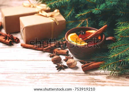 Hot mulled wine with orange, anise, cardamon and cinnamon on slate marble background. Christmas tree branches, gifts and cones. Flat lay, copy space, horizontal view. Holidays.