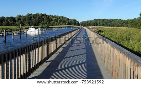 Chesapeake Beach Railroad Trail boardwalk along Fishing Creek with boat, Calvert County, Southern Maryland, USA