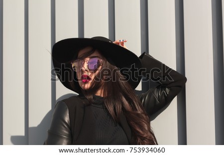 Lifestyle shot of stylish brunette woman with bright makeup and shiny hair posing in sun light