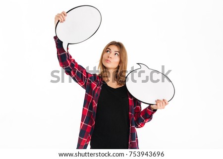 Portrait of a thoughtful pretty girl holding empty speech bubble and looking at camera isolated over white background