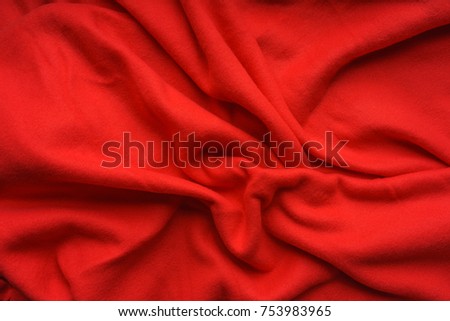 Red fabric fleece, wave, draperies. Beautiful textile backdrop. Close-up. Top view