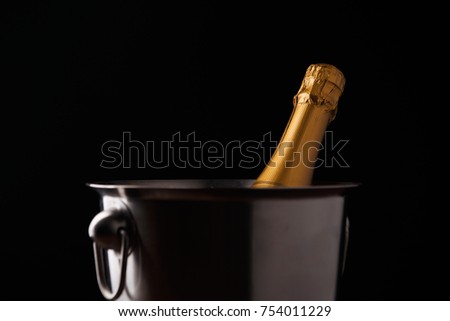 Image of bottle of champagne in iron bucket on black background