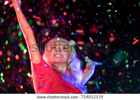 In selective focus of Cheerful young people showered with throwing confetti on a club party.Festival Event Party with People concept.Clubber drinking.