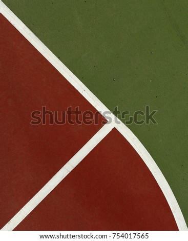 Pole aerial image of an outdoor basketball court. Includes red key, white lines, green surface and triangular shapes.
