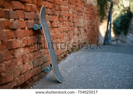 Skateboard leaning against old red brick wall