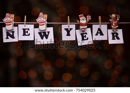 New year text on papers with clothespins with garland bokeh on background