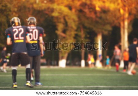 American football players at green field. Blurred image of game background.