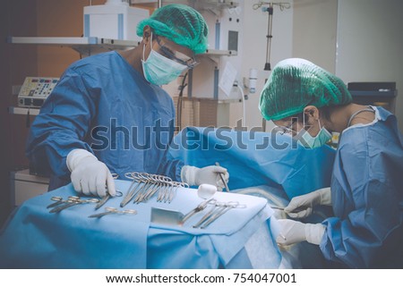 Surgeons team holding medical instruments performing surgery with patient sleeping on operation bed in operation room at hospital. Medical and Healthcare concept.