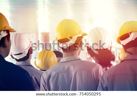Back turned group of young workers or engineers with yellow and white helmets  standing in construction site, lighting effect Royalty-Free Stock Photo #754050295
