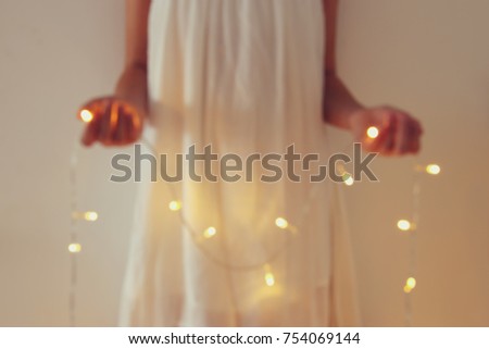 Abstract and bokeh image of young woman holding garland christmas lights