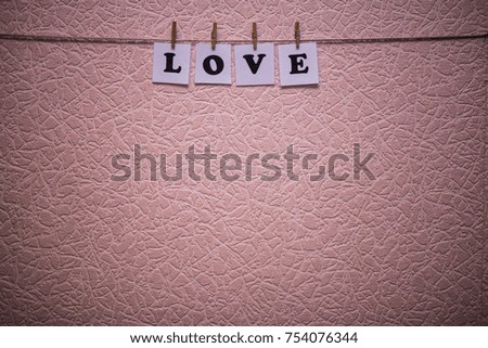 Love text on papers with clothespins with wall on background. Love concept
