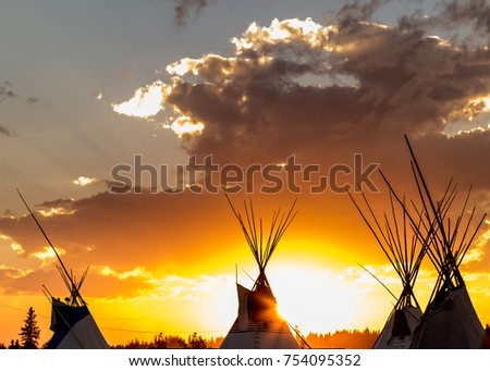 The tops of tee pees at sunset