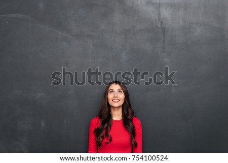 Picture of Happy brunette woman in red blouse looking up over black background