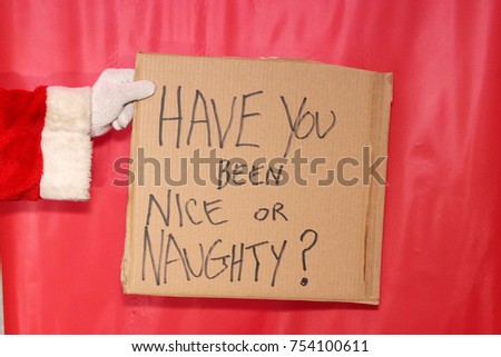 Santa Claus Sign. Santa Claus arm and hand holds a Cardboard Sign with messages against a red background.