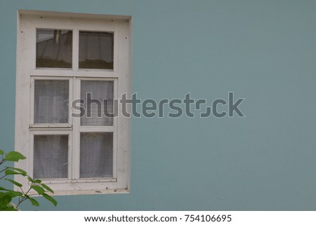 simple wooden window of an old country house, simplicity and beauty of forms and colors, white window frame over a blue wall