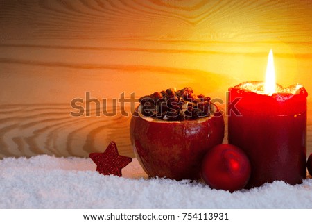 Avent candle and roasted apple with raisins isolated on wood background.