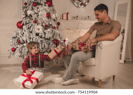 Father and son unwrapping presents on Christmas evening