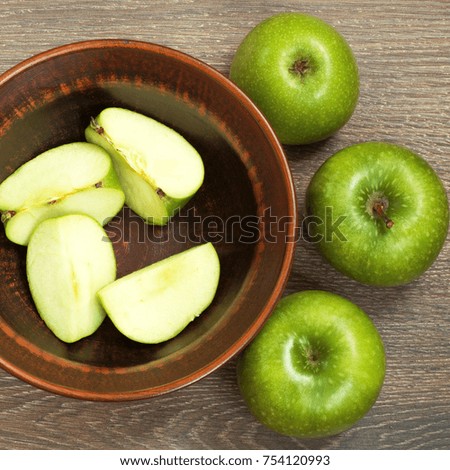Apples and slices of apples on the table top view. Green apples around a ceramic bowl with slices of appl closeup.