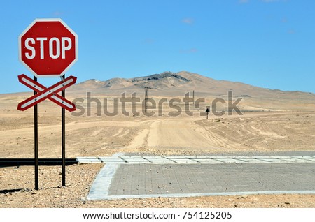 Dirt country road in Namib desert. There are railroads across the road. Rail crossing is marked by road signs. Namibia, Africa