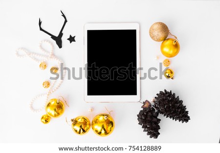 tablet display on table white screen for mockup in Christmas time. Christmas tree, gifts, decorations in background.