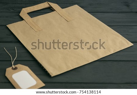A nice mock up for visualizing a corporate identity with a paper bag and a price tag. Kraft packaging and 	
label lie on a black vintage wooden table
 Royalty-Free Stock Photo #754138114