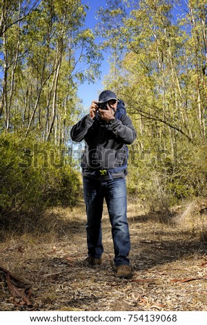 Hiker taking pictures in a forest, during a beautiful autumn day.