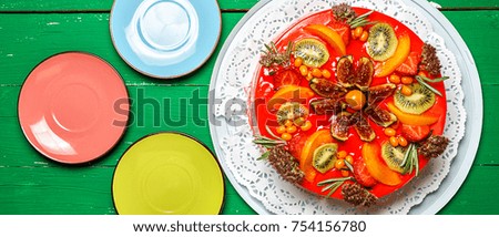 Delicious sweet fruit cheese cake on a green wooden background with colored saucers, border design panoramic banner 
