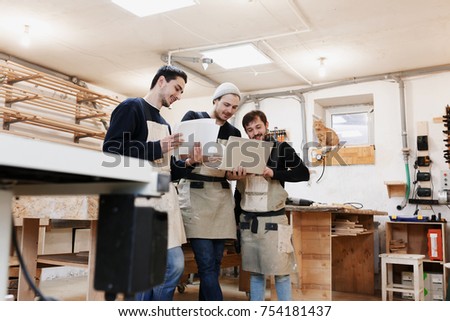 Master of small business with laptop and his team as sign of innovation in carpenter workshop. startup business, young specialist