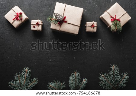 Christmas or New Year presents wrapped in paper and decorated with traditional Xmas twine and fir twigs on a black background Royalty-Free Stock Photo #754186678