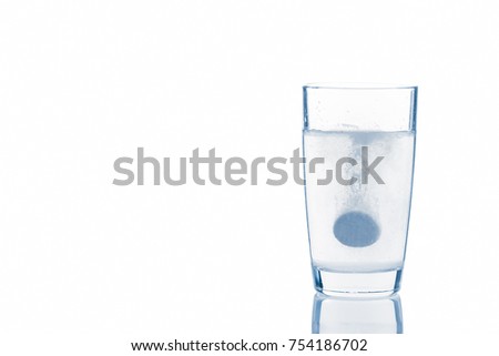 A soluble tablet dropped in a glass of water over white background Toned