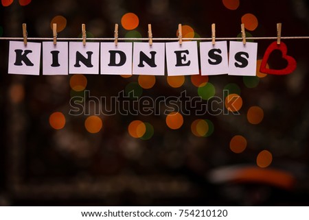 Kindness text on papers with clothespins with garland bokeh on background. The word "Kindness". Kindness concept