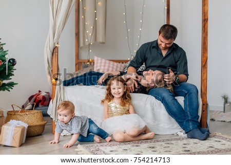 Young happy family of four having fun on bed near christmas tree. Happy new year concept.