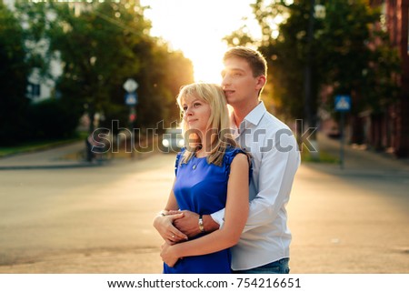beautiful couple in love with a woman walking in a park on a bench kissing at sunset and loving each other, a blue dress and a white shirt with jeans 1