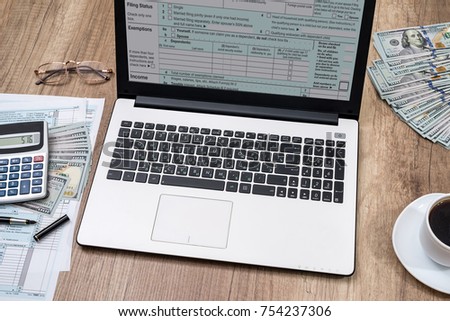 tax form, laptop, coffee and dollar on desk