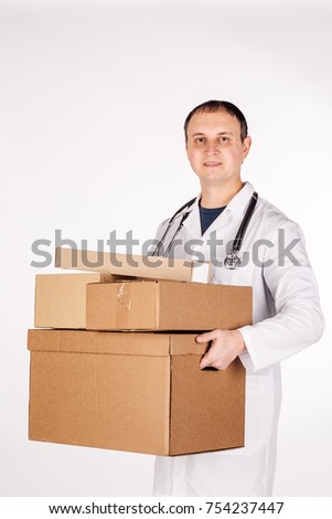 Young doctor smiling, holding box and looking at camera. image on a white studio background.